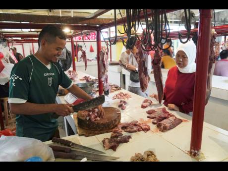 A butcher serves a customer at a market in Jakarta, Indonesia, during preparations to welcome the holy month of Ramadan.