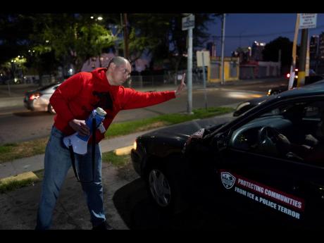 Ron Gochez, a teacher volunteering with Union del Barrio, an organisation advocating for immigrant rights, waves to other volunteers as they head out to search for ICE activity in a neighbourhood in Los Angeles on Thursday.