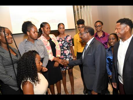 Nick Perry (second right), United States ambassador to Jamaica and Gary Williams (right), founder and chairman of Children of Jamaica Outreach (COJO), speak with scholarship awardees during the COJO Scholarship Awards luncheon at the AC Hotel in St Andrew 