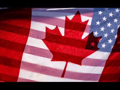 FILE - Sunlight shines through the flags of Canada and the United States, held together by a protester outside on Parliament Hill in Ottawa, February 1, 2025.(Justin Tang/The Canadian Press via AP, File)