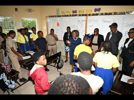 Minister of Education, Senator Dr Dana Morris Dixon (fourth right), interacts with grade-six students of Leeds Primary & Infant School in St Elizabeth during a visit to the institution on Thursday, March 13.  Sharing the moment are staff of the institutio