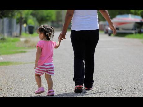 In this September 16, 2015, photo, a woman in Sullivan City, Texas, who said she entered the country illegally, walks with her daughter who was born in the United States, but was denied a birth certificate. 