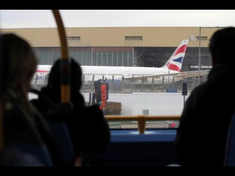 Passengers on a bus look at a parked plane as Britain's Heathrow Airport has closed for the full day Friday after an electrical substation fire knocked out its power, disrupting flights for hundreds of thousands of passengers at one of Europe's biggest tra