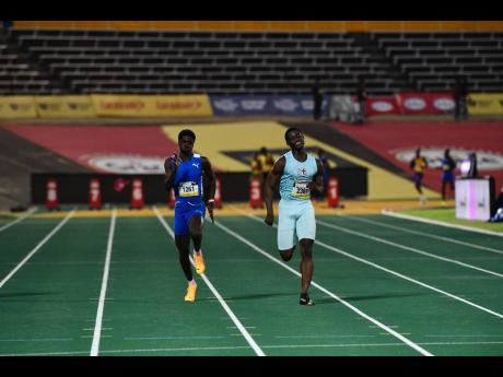 Clarendon College’s Roland Smith (left) and St George’s College’s Tyreece Foreman run in the sparsely populated heat four of the Class One boys’ 100 metres after four false starts at the ISSA/GraceKennedy Boys and Girls’ Athletics Championships i