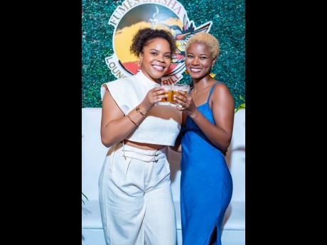 Gabrielle Watson (left), IT professional, and Shereen Reid, aerospace expert, raising a toast to womanhood in style. Watson keeps it chic in a crisp beige tailored set, while Reid stunned in a sleek cobalt blue dress with delicate floral earrings.
