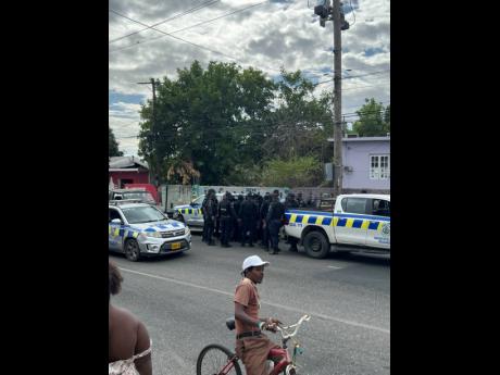 Law enforcement officers in discussion following a firefight with gangsters along Maxfield Avenue in St Andrew on Tuesday.