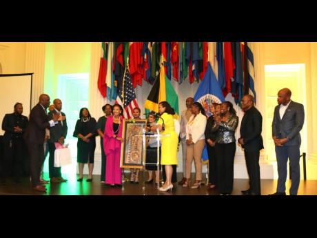 Senator Audrey Marks, former Jamaican ambassador to the United States and permanent representative to the Organization of American State (OAS), accepts a gift from Lishann Salmon, charge d’affaires at the Embassy of Jamaica, on behalf of members of staff