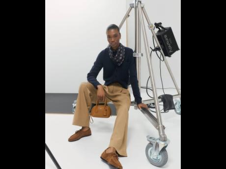 Naki Depass wears a silk detail cardigan, foulard LS print camp shirt, hazelnut pleat pants, and the Breeze mini-bag.