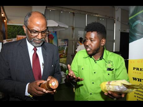 Nature’s Superfood Multivitamin business owner, Kraig Knight (right), shares insights about his company’s products on display at Expo Jamaica 2025 with Earl Jarrett, chief executive officer of the Jamaica National Group, during his tour on day two of t
