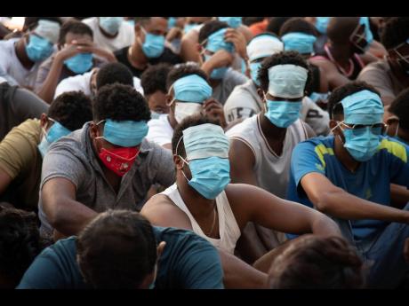 FILE - People from China, Vietnam and Ethiopia, believed to have been trafficked and forced to work in scam centres, sit with their faces masked while in detention after being released from the centres in Myawaddy district in eastern Myanmar, Feb 26, 2025.