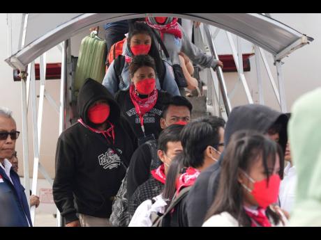 Indonesian nationals who had worked at scam centres in Myanmar disembark their plane upon arrival from Thailand, at Soekarno-Hatta International Airport in Tangerang, Indonesia, March 18, 2025. 