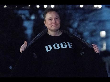 Elon Musk flashes his DOGE T-shirt to the media as he walks on the south lawn of the White House, in Washington, March 9, 2025.