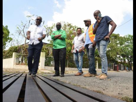 From left: Mayor of Portmore Leon Thomas points to a drain on Texas Avenue in Independence City, Portmore, that he believes is the cause of houses being damaged in the area, to Desmond McKenzie, minister of local government and community development, durin