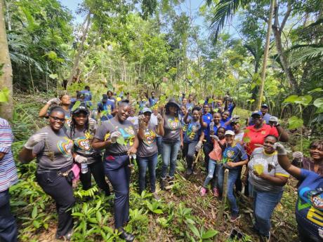 Excited volunteers and representatives of the Forestry Department, Sandals Foundation, Jamaica Fire Brigade, and the Moneague Primary School show off their tree seedlings planted among 300 timber trees to support forest cover in the Bogue 2 Forest Reserve,
