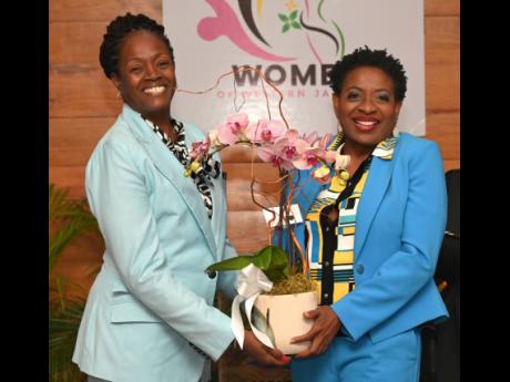 Chorvelle Johnson-Cunningham (left), CEO of Sagicor Bank, accepts an orchid from Janet Silvera, founder and chair of the Women of Western Jamaica (WOWJa) movement, during the organisation’s breakfast launch at the Montego Bay Convention Centre in Rose Ha