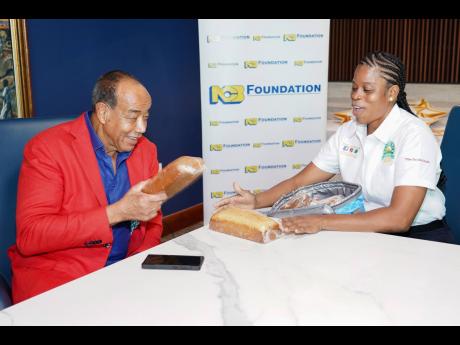 St James farmer Nadesha Campbell showcases her proposed cassava bread product to businessman Michael Lee-Chin during a meeting in February 2025.