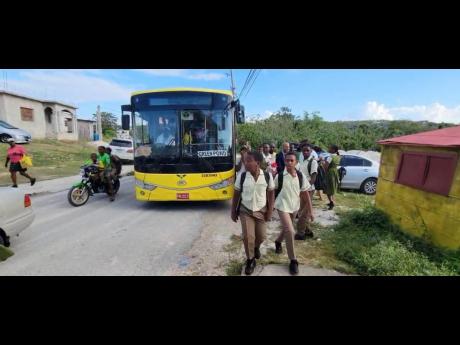 Students of Green Pond High School in St James walking towards the gate of their school after disembarking from a Montego Bay Metro bus on Monday morning.