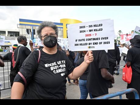 Jamaicans for Justice spokesperson Susan Goffe holds aloft a placard during the protest.