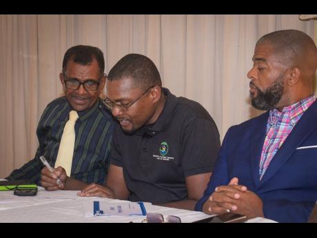 Minister without Portfolio in the Ministry of Economic Growth and Job Creation with Responsibility for Works, Robert Morgan (centre), converses with President, St Catherine Chamber of Commerce and Industry, Dennis Robotham (left) on April 30 during the org