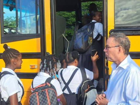 Students boarding the school bus in Buff Bay, Portland, while Transport Minister, Daryl Vaz, looks on.