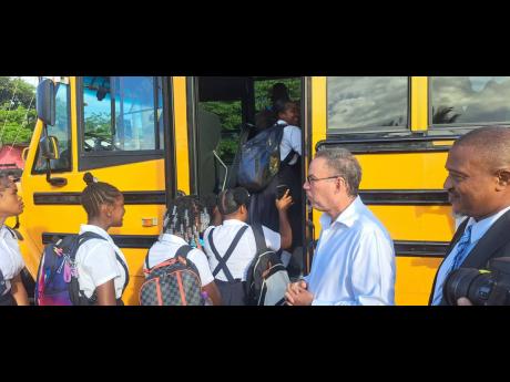 Students board the school bus in Buff Bay, Portland, while Transport Minister Daryl Vaz looks on. 
