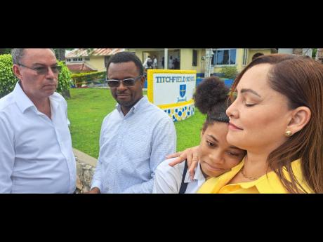 Ann-Marie Vaz, member of parliament for East Portland, offers comfort to Ronika Silveria, a 14-year-old student of Titchfield High School who is a survivor of a fatal accident that occurred in May last year, claiming the lives of two students from that sch