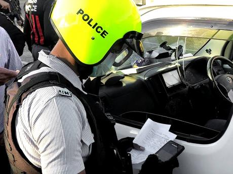 Credit: File A policeman utilising the e-ticketing system to check a motorist’s car documents.
