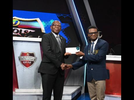 Northern Caribbean University (NCU) President Professor Lincoln Edwards presents a scholarship offer letter to Alex Anderson, captain of Titchfield High School’s quiz team, which won TVJ’s Schools’ Challenge Quiz 56th season on April 8, defeating Jam