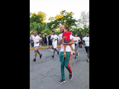 Credit: Contributed Reality White, lab technician at the University of Technology, Western Campus, carrying his two-year-old son, Amir, in his arms while doing the 5K Walk during the Jill Stewart MoBay City Run event at the Harmony Beach Park on Sunday.
