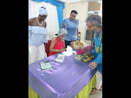 Dr Monica E. Taylor autographing a copy of her book, ‘My Juneplum Journey - Living with multiple myeloma’, as (from left) Dr Carmeneta Jones, Dr Vivette Milson-Whyte, Dr Caroline Dyche, some of her former University of the West Indies co-workers from t