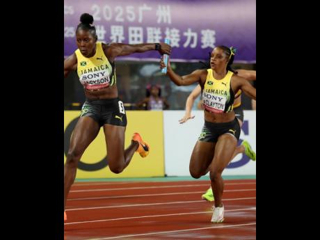 Jamaica’s Shericka Jackson (left) receives the baton on anchor leg from Tia Clayton during the World Athletics World Relays 4x100 metres at the Guangdong Olympic Stadium in Guangzhou, China, yesterday.