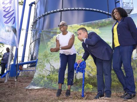 Minister without Portfolio in the Ministry of Economic Growth and Job Creation, Matthew Samuda (centre), takes a sip of water from the new 50,000-gallon steel tank in Mount Prospect, St Andrew, during the commissioning ceremony on May 8.  Sharing the momen
