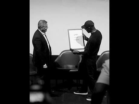 Dr Mykaell Riley (right) views the Rockschool RSL Fellowship award, which was presented to him earlier by RSL Awards founder, Norton York, (left).