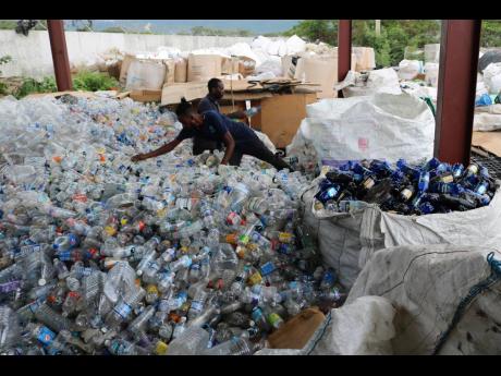 Workers at the Recycling Partners of Jamaica depot in St Catherine cull the coloured bottles from among the many thousands which are collected each day for processing prior to being exported. The bottles are sorted by colour and then baled accordingly.