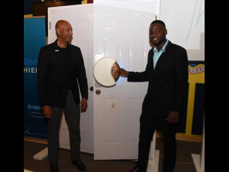 Rayvon Stewart (right), chief executive officer, Xermosol, shows off one of the XermoShield smart self-sanitising door handles to Dr David Lowe (left), managing director, Development Bank of Jamaica (DBJ), during a soft launch of the product at the Hugh Wy