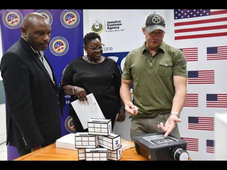 A United States official from the Bureau of International Narcotics and Law Enforcement Affairs (INL) demonstrates the features of a donated mass spectrometer to Kalista Powell, director of the Contraband Enforcement Team (CET), and Dave Hanson, manager, C