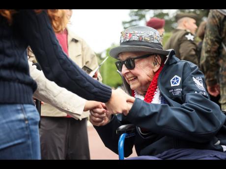 World War II veteran Jake Larson meets youths during ceremonies at the US cemetery to commemorate the 81st anniversary of the D-Day landings, Friday, June 6, 2025 in Colleville-sur-Mer, Normandy. (AP Photo/Thomas Padilla)