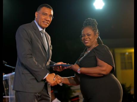 Prime Minister Dr Andrew Holness presents senior teacher at The Manning’s School, Audrey Williams Woolery, with the Prime Minister’s Medal of Appreciation for Service to Education, at Jamaica House on May 28.