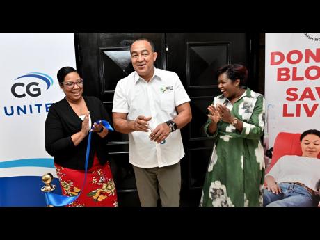 Christopher Tufton, Minister of Health and Wellness, cuts the ribbon with Winsome Gibbs (right), branch manager of UG United Insurance Jamaica, and Keishawna Pinnock (left), assistant blood donor organiser at the National Blood Transfusion Service (NBTS), 
