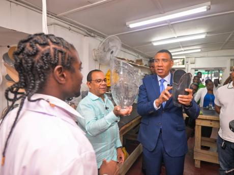 Prime Minister, Dr Andrew Holness (second right), speaking to Prosthetic Technician, Jerome Walters (left), about the process of creating prostheses, during a visit to the Surgix Prosthetics Clinic at the Sir John Golding Rehabilitation Centre in St Andrew