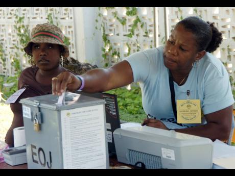 An election day worker places a ballot in a box during the 2024 local government elections.