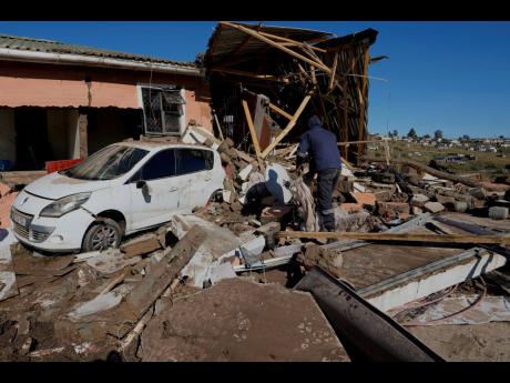 A resident looks through the remnants after floods swept through the area in Mthatha, South Africa, Thursday, June 12, 2025. (AP Photo/Themba Hadebe)