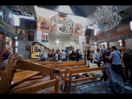 Syrian citizens and security forces inspect the damage inside Mar Elias church where a suicide bomber detonated himself in Dweil'a in the outskirts of Damascus, Syria, Sunday June 22, 2025. (AP Photo/Omar Sanadiki)