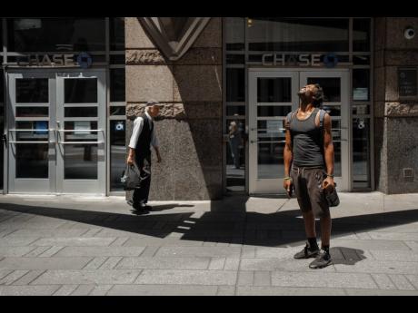 A man squints at the sun during a heatwave on Tuesday, June 24, 2025, in New York. (AP Photo/Olga Fedorova)