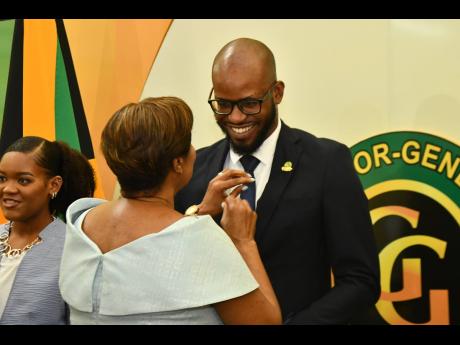 Lady Allen, wife of Governor General Sir Patrick Allen, pins Gleaner journalist Jovan Johnson in the category of St Andrew Awardee 25-35 years old during the Governor General’s Achievement Awards Ceremony held yesterday at King’s House in St Andrew.