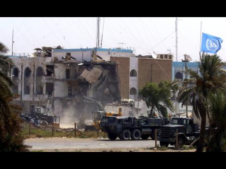 US military vehicles pass the collapsed section of the United Nations headquarters Saturday, August 23, 2003, in Baghdad, Iraq.
