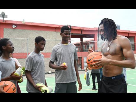 San Antonio Spurs’ Devin Vassell (right) signs his autograph on shoes for athletes from western Jamaica, who received Nike gear, during the Devin Vassell Basketball Clinic at Herbert Morrison Technical High School in Montego Bay, St James, yesterday.