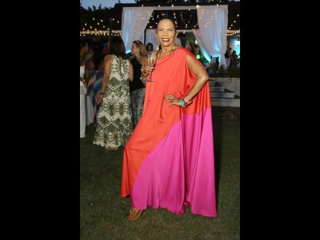 Entrepreneur Cecile Levee exudes island luxe in a two-tone coral and fuchsia caftan, complemented by bold bangles and a bright red lipstick.
