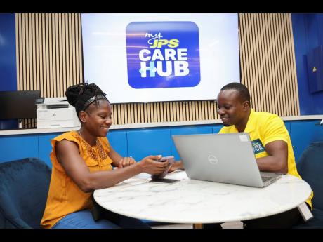 JPS representative, Christopher Ellis (right), assists Nicole Stanley, the first customer to be served at the company’s new JPS MyCare Hub inside Fontana Pharmacy in Portmore. The JPS MyCare Hub was launched on  July 7, marking the latest step in the com