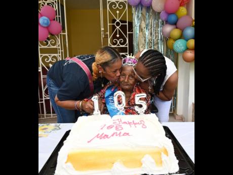 Enid Dennis gets birthday kisses from daughters Cheryl Dennis (left) and Marcia Nelson.